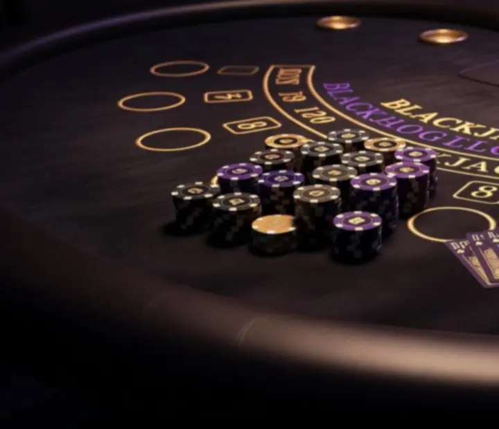 Detal stołu blackjack z żetonami i kartami w eleganckim, ciemnym otoczeniu.